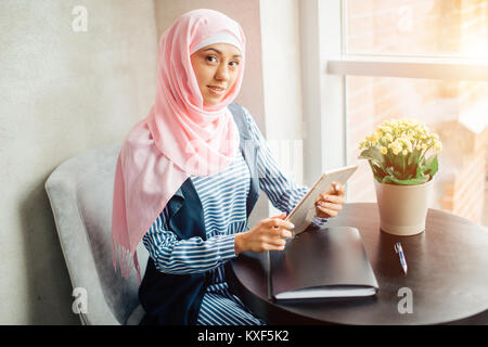 Musulmani femmina studente di college utilizzando computer tablet in cafe Foto Stock