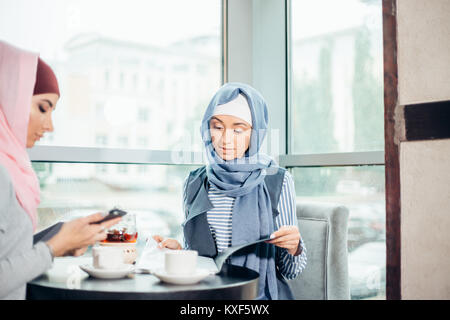 Musulmani donna business documenti di lavoro in cafe Foto Stock