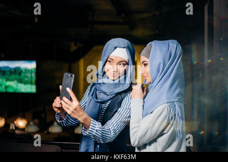 Due donna musulmana selfie amico tramite smartphone Foto Stock