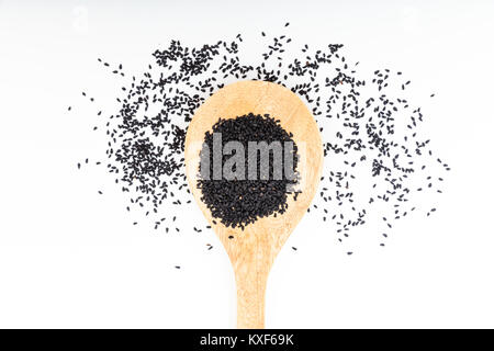 Di semi di sesamo nero in un cucchiaio di legno su sfondo bianco Foto Stock