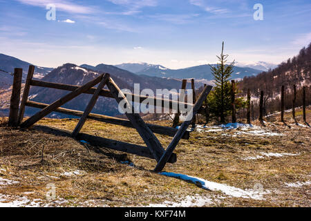 Rotture di recinzione di legno sulla collina. La primavera è in arrivo. bellissimo paesaggio di montagna con un po' di neve sulle piste con erba spiovente su un luminoso giorno Foto Stock