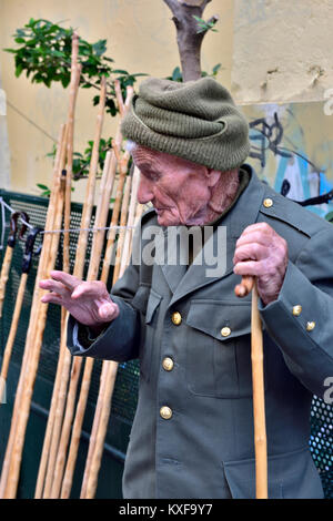 Uomo anziano superiore di contenimento del bastone. Egli produce e vende bastoni da passeggio per il mercato locale, Atene, Grecia Foto Stock