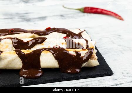 Pollo alla messicana enchiladas con peperoncino Salsa di cioccolato mole poblano. Tradiional cucina latino americana. Foto Stock