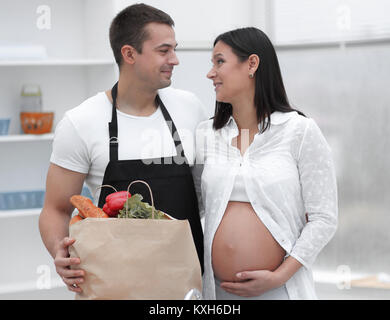 Il marito e la moglie incinta pettinatura sono attraverso il pack,in piedi in cucina Foto Stock