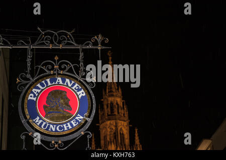 Monaco di Baviera, Germania - 17 dicembre 2017: Birra Paulaner logo nella parte anteriore di Monaco e Municipio nuovo (Neues Rathaus) a notte. Paulaner Bier è uno dei simboli Foto Stock