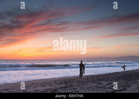 Un surfista guarda fuori all'oceano dopo una sessione al tramonto a El Porto Spiaggia. Foto Stock