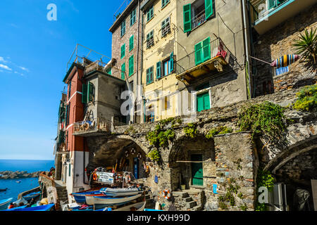 Le case colorate, barche, il mare e la marina al borgo di Riomaggiore, Italia, sulla costa ligure delle Cinque Terre, Italia Foto Stock