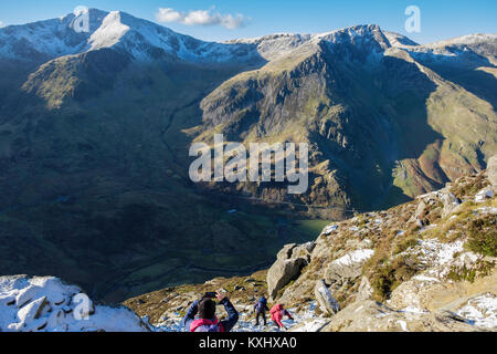 Gli escursionisti escursionismo fino Pen yr Ole Wen montagna con la neve in inverno nelle montagne del Parco Nazionale di Snowdonia Y Garn e Foel Goch al di là. Ogwen Conwy Wales UK Foto Stock