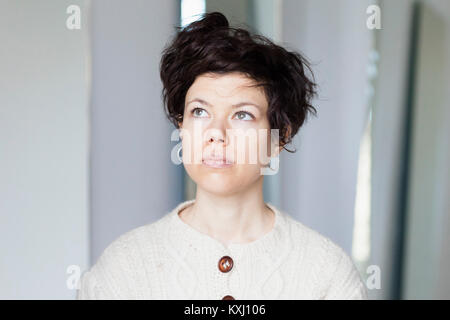 Primo piano di donna premurosa con capelli corti che guardano via Foto Stock
