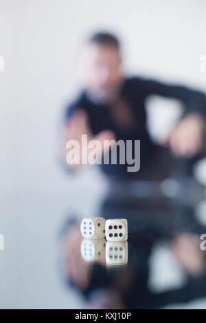 Uomo d'affari che rotola dadi su tavolo di vetro Foto Stock