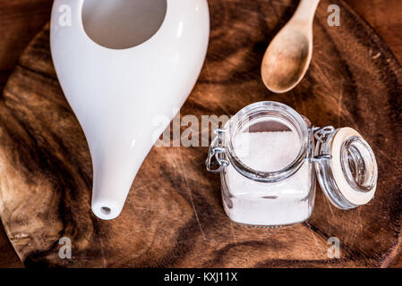 Neti pot, ayurvedico strumenti per la pulizia del naso con acqua e con acqua e sale, vista dall'alto, tavolo in legno e la scheda sullo sfondo Foto Stock