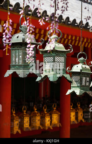 Tre ornati lanterne di metallo appeso a un tempio giapponese. Profondità di campo con il fuoco selettivo sul medio lanterna. Foto Stock