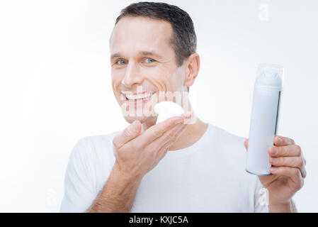 Positivo l'uomo felice tiene una schiuma da barba Foto Stock