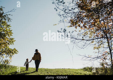 Madre e figlia camminando mano nella mano in ambiente rurale Foto Stock