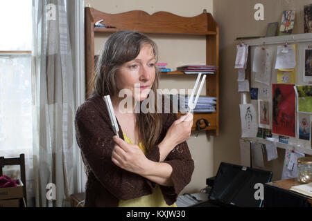 La donna che soffre di ipersensibilità elettromagnetica intolleranza sindrome (EHS) tenendo la guarigione Diapason e dorme all'interno di una gabbia di Faraday, REGNO UNITO Foto Stock