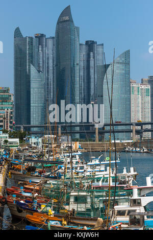 Righe di vecchie barche da pesca ormeggiate a Centum city, Busan, in contrasto con i moderni grattacieli per la parte posteriore. Corea del Sud. Foto Stock