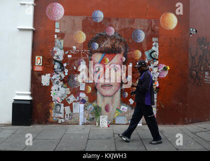 Un uomo cammina passato un murale di David Bowie in Brixton, Londra per il secondo anniversario della sua morte. Foto Stock