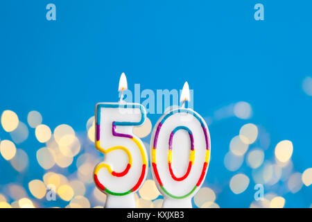 Numero 50 celebrazione di compleanno candela contro un luci luminose e sfondo blu Foto Stock