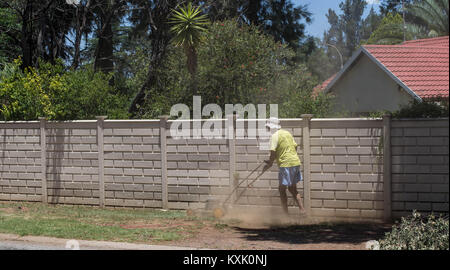 Johannesburg, Sud Africa - un proprietario di abitazione non identificato mows quello che è a sinistra del suo prato in grave siccità e condizioni di calore nel paese Foto Stock