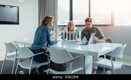Imprenditore dando la presentazione ai colleghi alla riunione. La gente di affari presso la sala conferenze guardando il laptop. Foto Stock