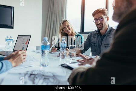 Giovane imprenditore in riunione con i colleghi di lavoro nella sala conferenza. Professionisti creativi che discutere di affari in board room. Foto Stock