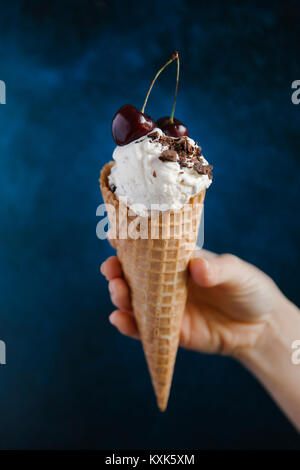 Ritagliate la mano della donna che mantiene il gelato contro sfondo colorato Foto Stock