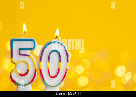 Numero 50 celebrazione di compleanno candela contro un luci luminose e sfondo giallo Foto Stock