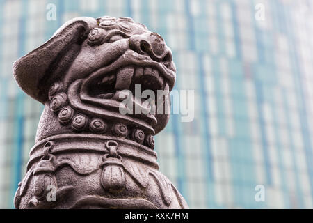 Close up di un cinese lion statua su una rotatoria su Holloway Circus in Birmingham., sostenuta da un nuovo grattacielo. Foto Stock