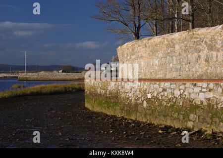 La Capra a piedi, vecchio Seawall stretto sentiero lungo la sponda est del fiume Exe Estuary, Topsham, Devon, Regno Unito. Gennaio, 2018. Foto Stock