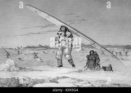 Un eskimaux di igloolik indossando un uccello-Giacca pelle, portando la sua canoa all'acqua Foto Stock