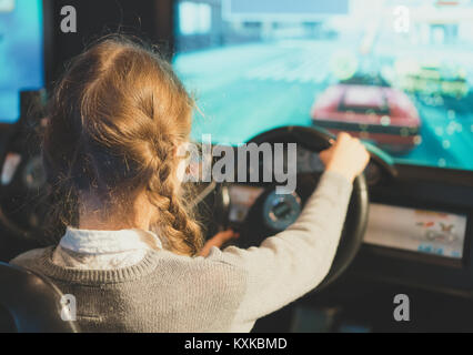 Bambina giocando racing simulatore di gioco nel parco a tema. Foto Stock