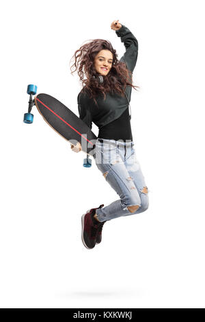 Overjoyed teen ragazza con un longboard jumping isolati su sfondo bianco Foto Stock