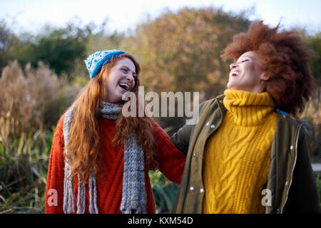 Amici a braccetto di gettare la testa indietro ridendo Foto Stock