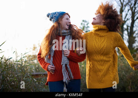 Amici a braccetto di gettare la testa indietro ridendo Foto Stock