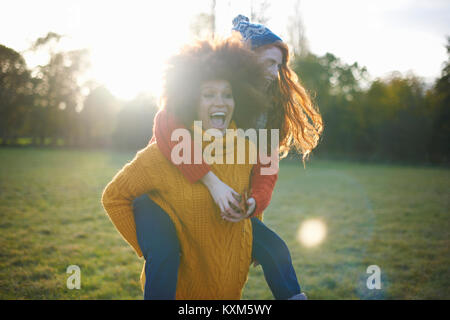 Due giovani donne,in ambiente rurale,giovane donna dando amico piggyback ride Foto Stock