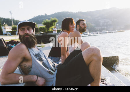 Tre giovani hipsters seduto a guardare il lago di Como, Como,Lombardia,Italia Foto Stock