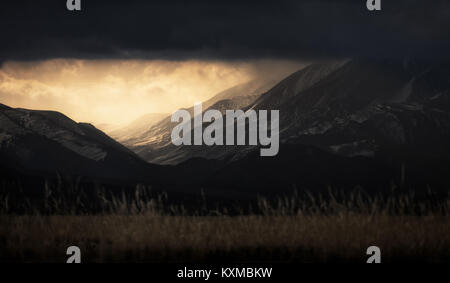 Nuvole drammatico aprendo la luce del tramonto montagne innevate neve Mongolia steppe praterie pianure raggi del sole Foto Stock