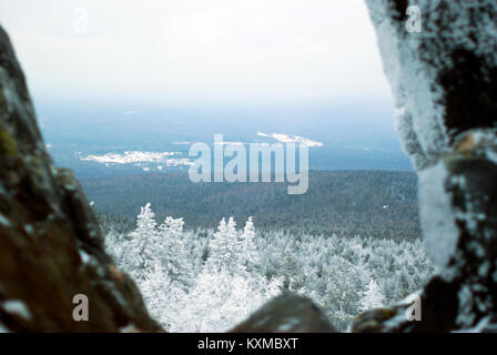 Vista in nuvoloso meteo invernale sulle colline boscose dalla cima della montagna in uno spazio tra due naturale massi di pietra Foto Stock