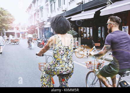 Multi etnico hipster giovane in bicicletta lungo una strada di città,Shanghai Concessione Francese,Shanghai, Cina Foto Stock