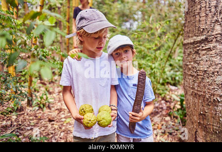 Ragazzi nella giungla azienda noci di cocco e seme,Aguas Calientes,Chuquisaca,Bolivia,America del Sud Foto Stock