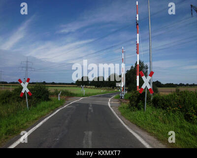L'attraversamento ferroviario di Rosenhagen, in una zona di lingua tedesca, presenta binari, barriere, attrezzature di segnalazione e aspetti delle operazioni di trasporto ferroviario. Foto Stock