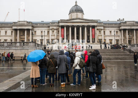 Londra, Regno Unito. Xi gen, 2018. Un gruppo di turisti congregates sotto la pioggia in Trafalgar Square. Credito: Mark Kerrison/Alamy Live News Foto Stock