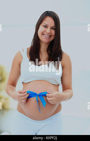 Donna incinta legata a prua blu sul suo bambino bump. Foto Stock