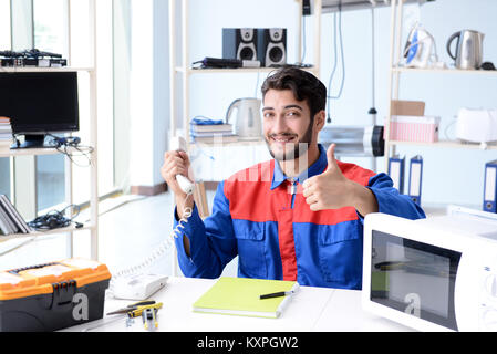 Giovani aggiustatore di fissaggio e la riparazione di un forno a microonde Foto Stock