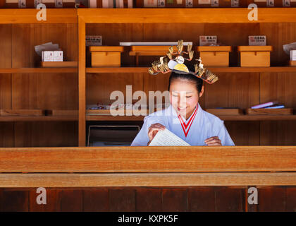 OSAKA, Giappone - 24 ottobre: Santuario aiden di Osaka in Giappone il 24 ottobre 2014. Unidentified 'Miko' a Sumiyoshi Taisha nel contatore vendere wi Foto Stock