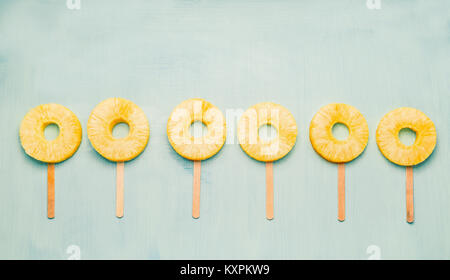 Fetta di ananas popsicles sulla luce sfondo turchese, vista dall'alto. Cibo sano e mangiare vegetariano concept Foto Stock