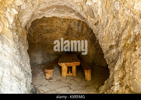 Tavolo in legno con due panche in pietra di una stanza. Camere in pietra della Georgia.viaggio in Georgia Foto Stock