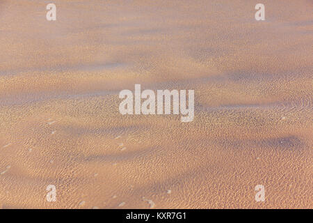 Close-up di acqua di mare ondeggiano delicatamente su una spiaggia sabbiosa. Foto Stock