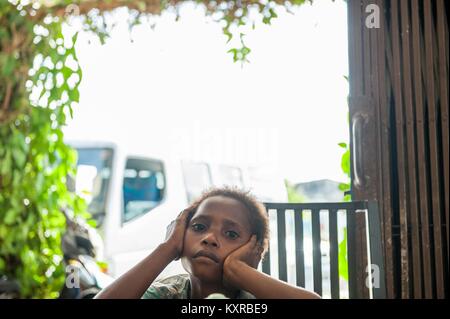 Unidentified ragazzo di una tribù asmat su sfondo luminoso, telaio di piante verdi . Nuova Guinea isola. Maggio 22, 2016 Foto Stock