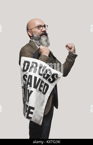 L'uomo mostra poster con uno slogan, isolata su uno sfondo grigio Foto Stock